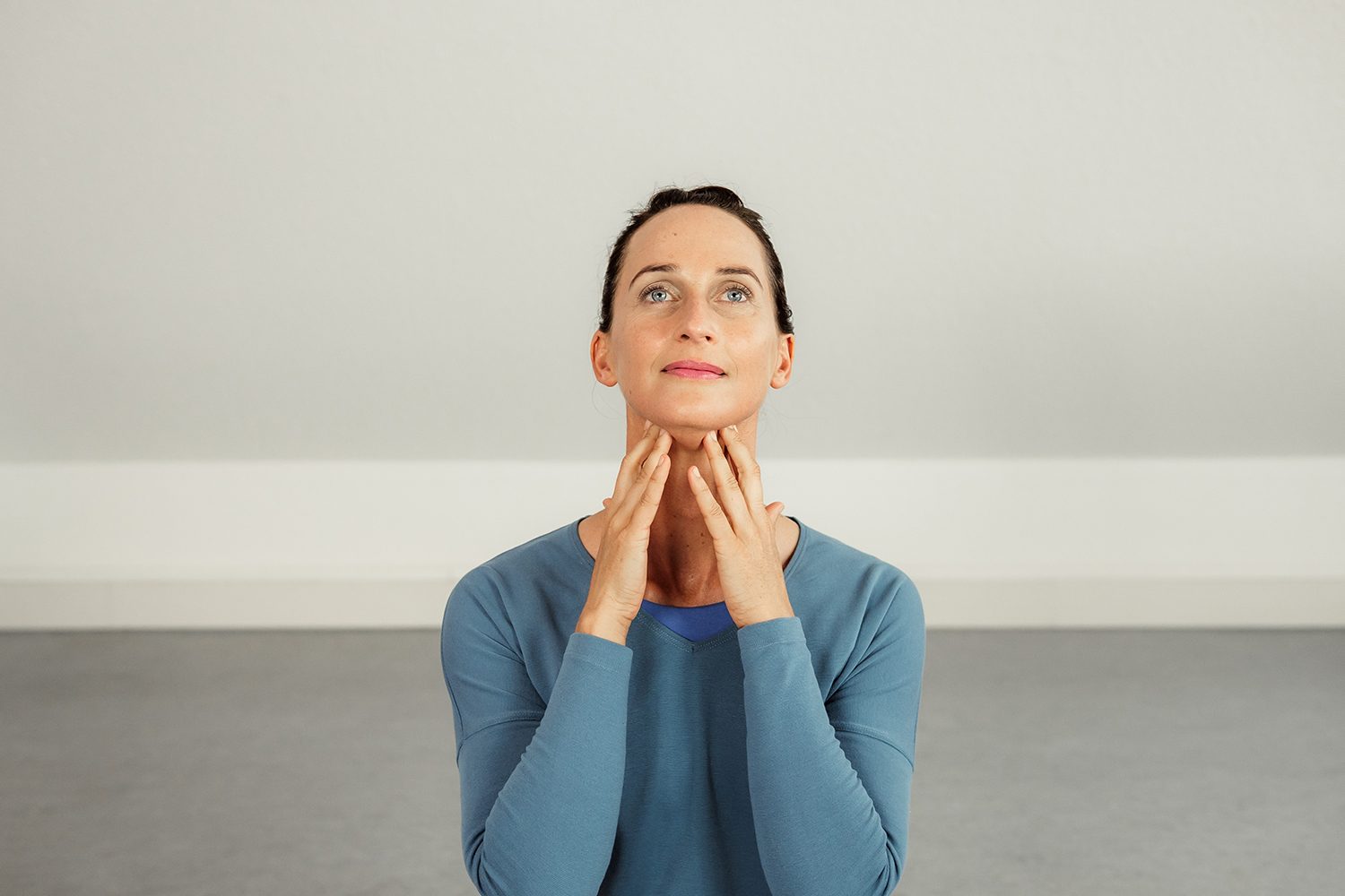 Osteopathin fasst sich mit beiden Händen an den Hals